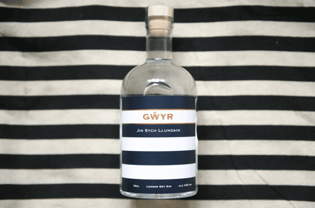 A bottle of gin on a blue and white stripe background